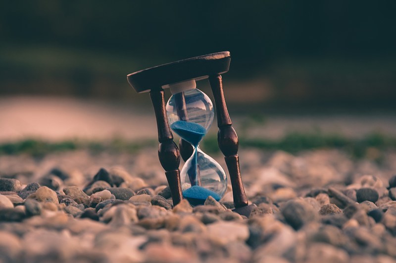 blue sand falls in an hourglass on a rocky beach, life is like an hourglass 4k