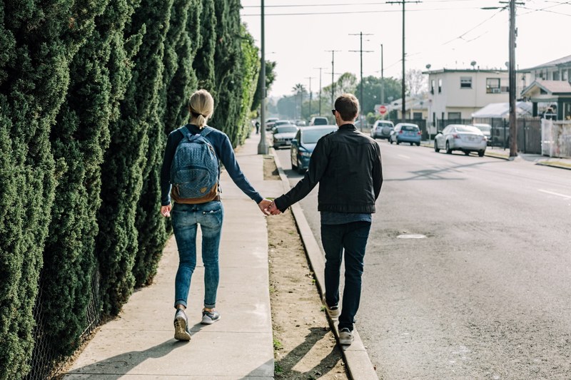 a couple walks holding hands one on the sidewalk and one on the curb, glendale couple 4k