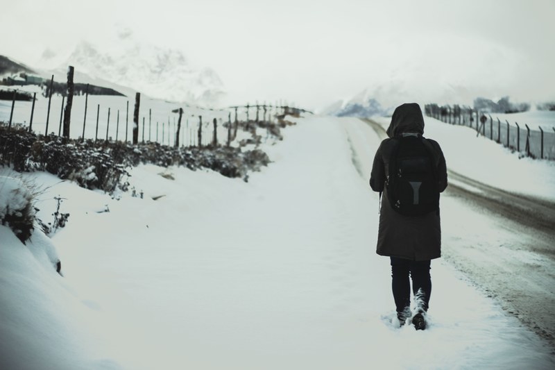 a person walking alongside a fence on a snow covered country road in ushuaia in argentina, cold walk 4k