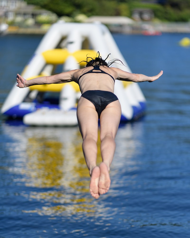 a fit woman in a black bikini dives into blue water, committed 4k