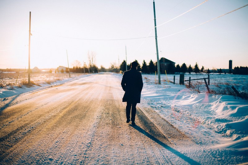 a silhouette of a person walking on a snow covered road, a freezing morning 4k