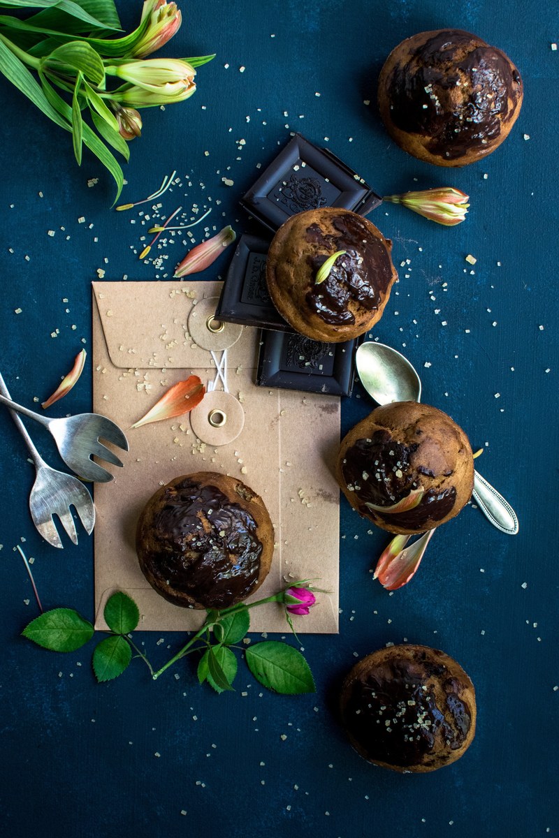 drone view of cupcakes chocolate squares and flowers on top of a brown closed envelope, banana muffin with dark chocolate 4k