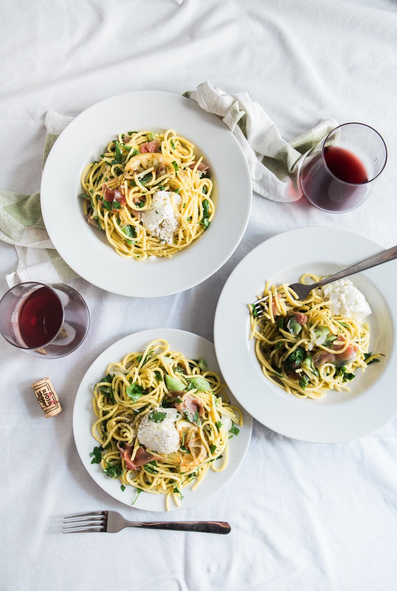 an overhead shot of two glasses of red wine next to three plates of pasta with pancetta on a white tablecloth, pasta in amorebieta 4k