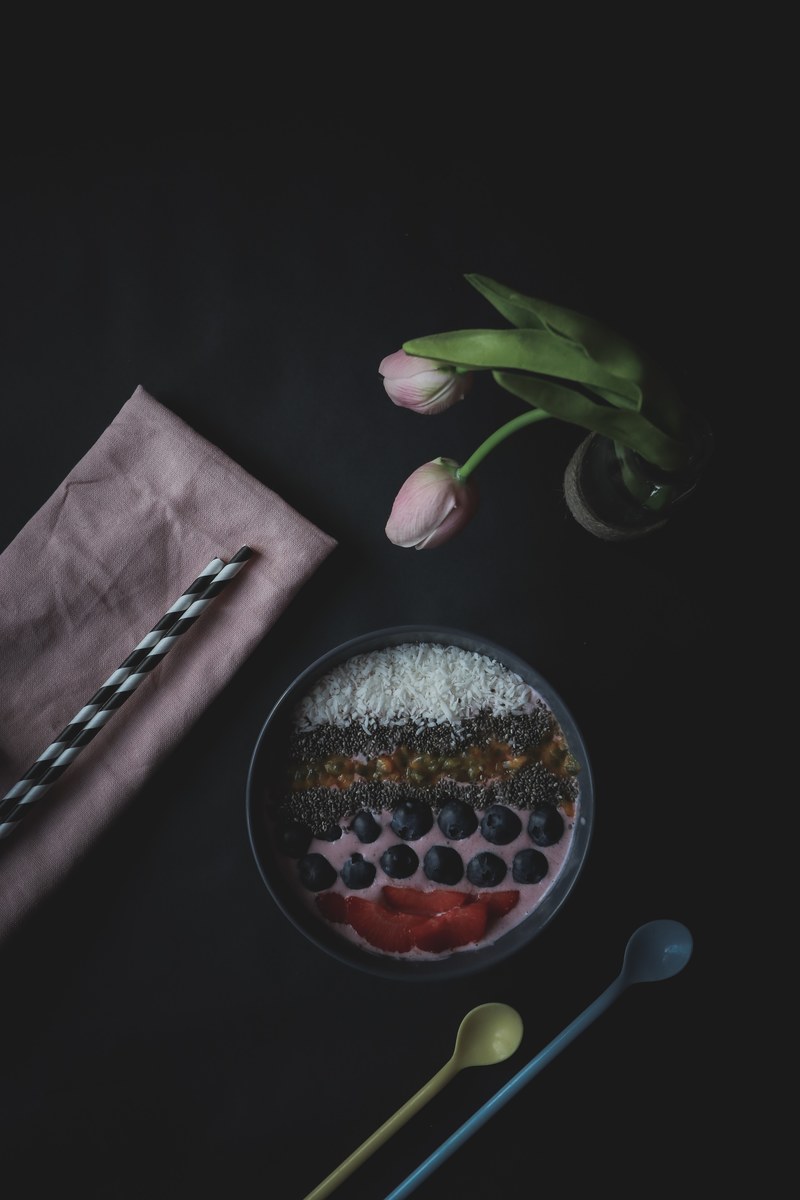 a flat lay shot of a fruit dessert a vase of roses spoons straws and napkin, _smoothie bowl 4k