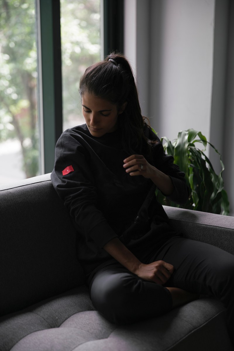 woman on the couch looking at the logo on her sweater sleeve, the urban explorer sweatshirt 4k