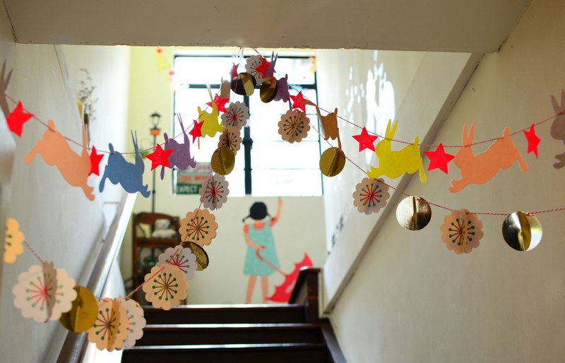 a school hallway decorated with bunnies stars and polka dots with a girl holding an umbrella painted on the wall in singapore, singapore school hallway 4k