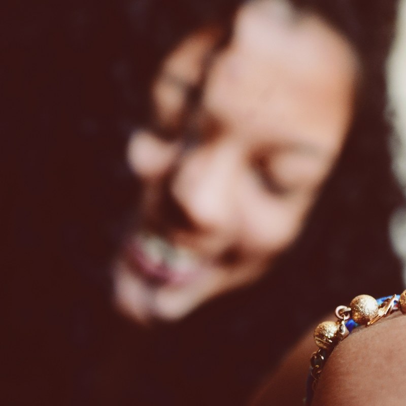 a smiling woman with a blurred face holding forward a bracelet on her wrist, blurred woman with bracelet 4k