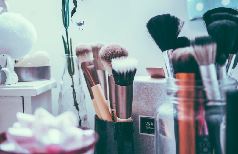 a sparkly cup of makeup brushes surrounded my a vase with a plant and a jar of more makeup brushes, beauty salon brushes 4k