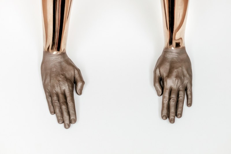 sculpture of golden arms and human hands resting on a white surface in fundaco serralves, golden arms in fundaco serralves 4k