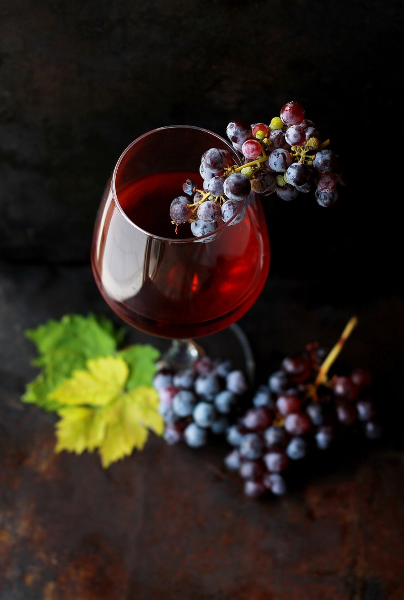macro view of a wine glass containing alcoholic wine with a bunch of grapes, wine and grapes from above 4k