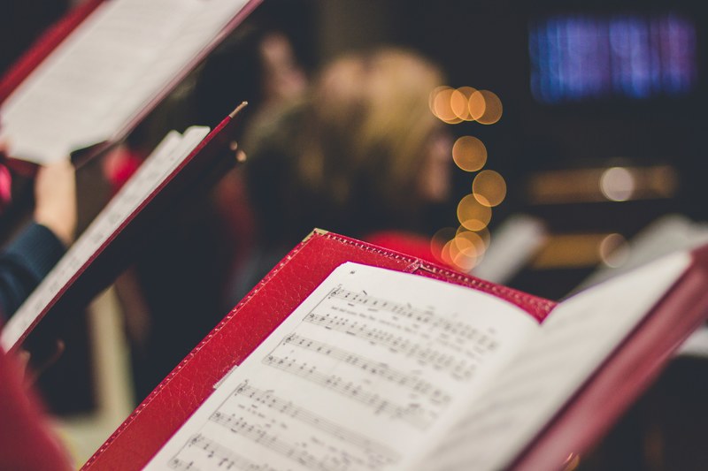 a close up of a music score in a red leather case with bokeh effect in the background, chorus sheet music 4k