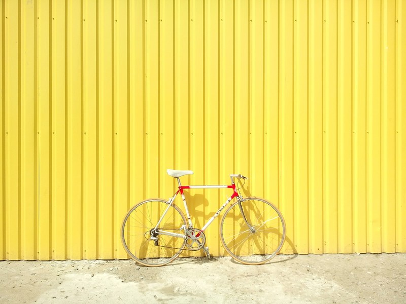 a vintage bicycle leaned against bright yellow wall, bicycle against yellow wall 4k