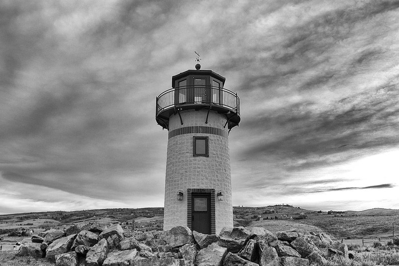 black and white shot of traditional lighthouse near rocks with cloudy sky, monochrome lighthouse rocks 4k