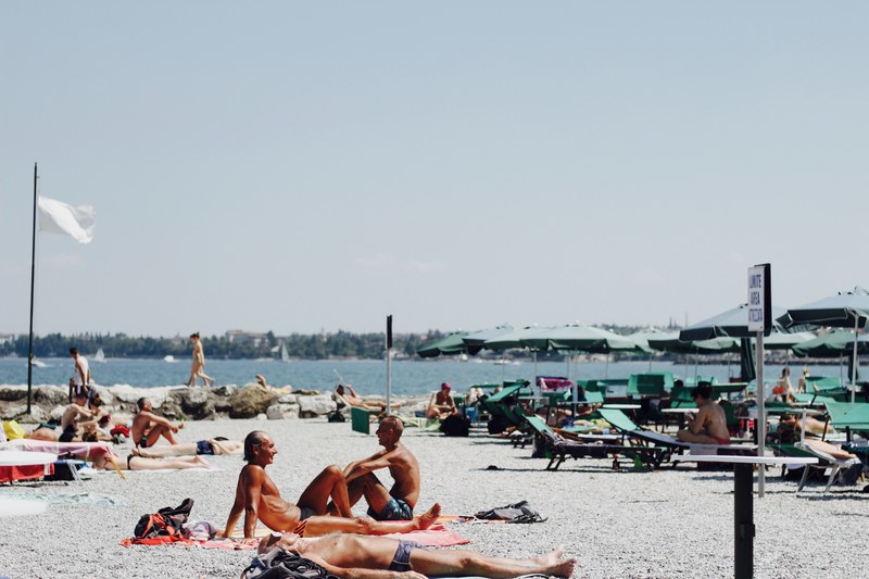 people sunbathing on a beach on a lake, sunbathing by a lake 4k