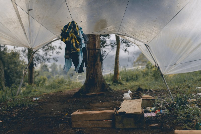 a tent filled with clothing wood and empty plastic bottles, tent and supplies 4k