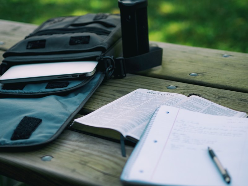 a notebook and a bible on a bench next to a bag with a laptop, students homework 4k