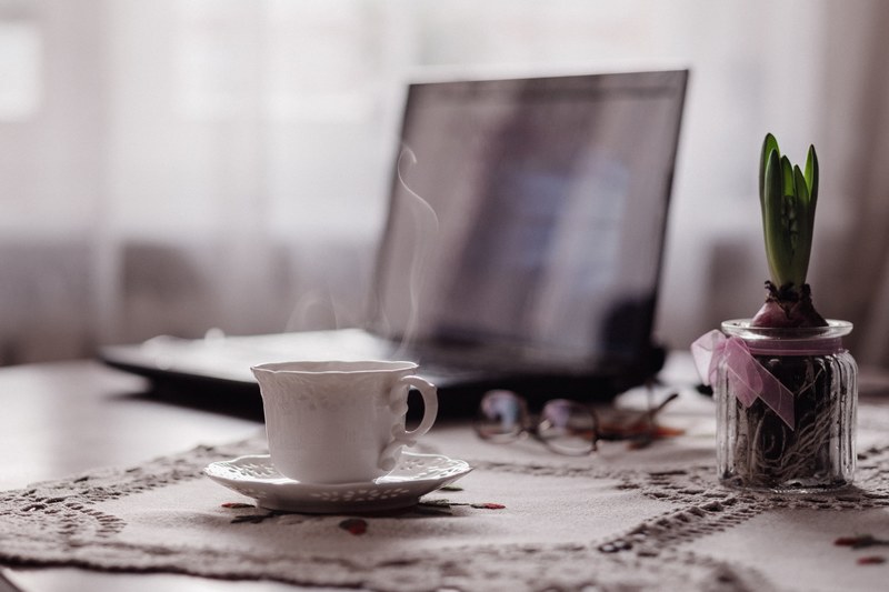 a cup of hot coffee next to a laptop and a potted flower bulb, potted flower bulb and coffee 4k
