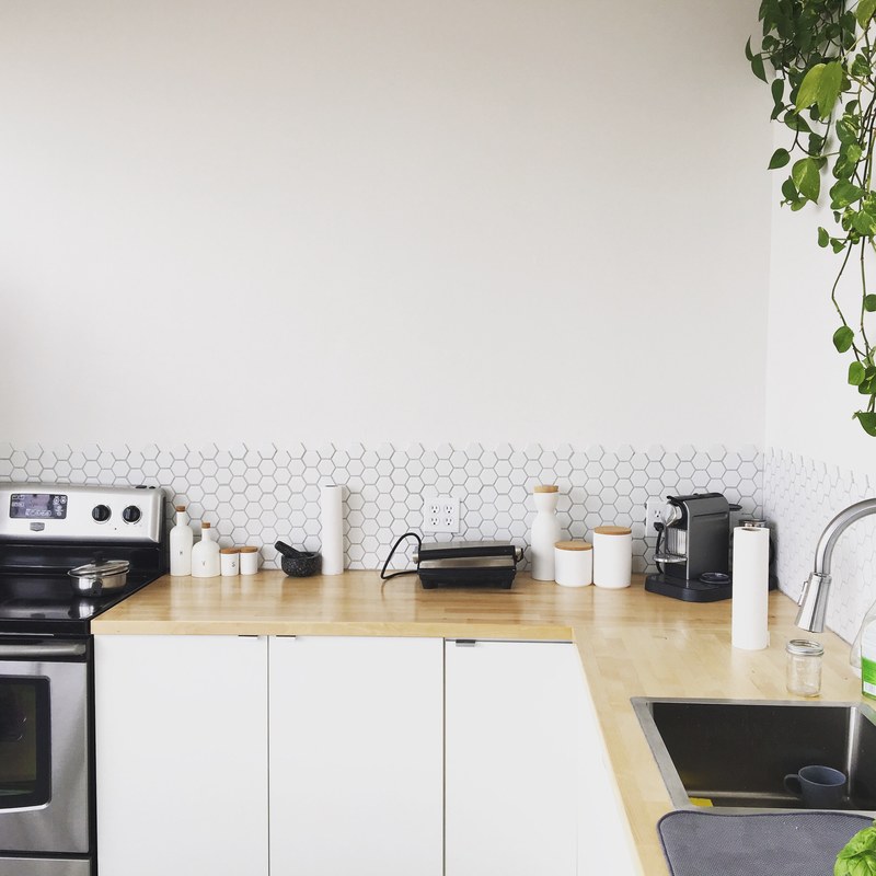 sparsely decorated kitchen with wooden counter oven plant and tiled backsplash, a clean kitchen 4k