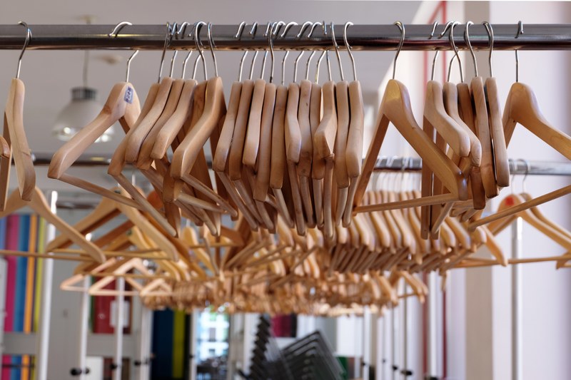 a macro shot of coat hangers on a rail in a clothing store, clothes hangers on railing 4k