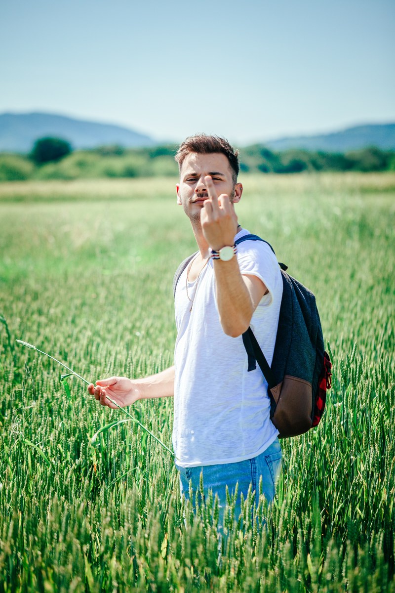 young guy in wheat field showing middle finger 4k
