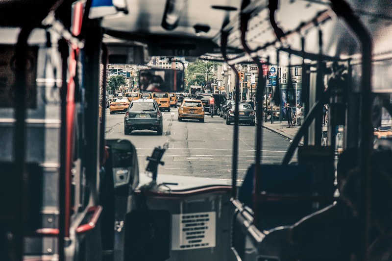 a shot looking through a public bus through the windshield onto a street filled with cars and taxis, we dont take the bus often enough 4k