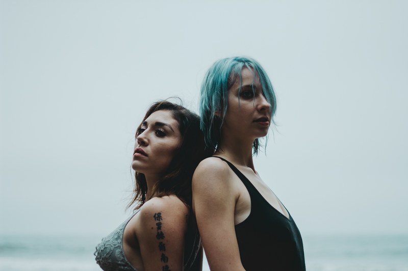 two women standing back to back at pismo beach, women standing back to back 4k