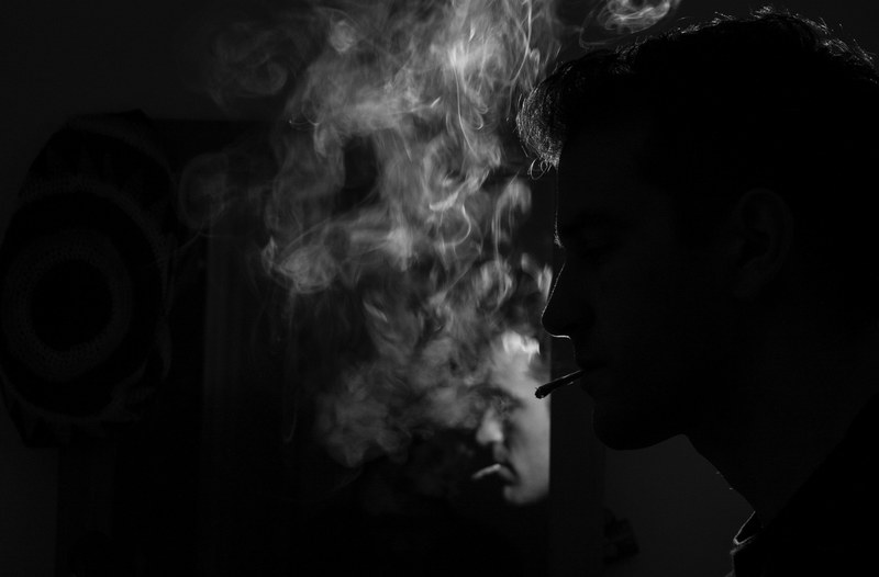 black and white shot of young man smoking a cigarette in barcelona with mirror reflection, man smokes in barcelona 4k