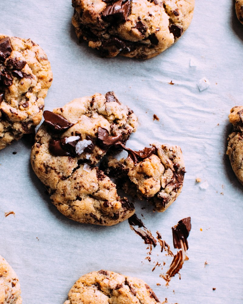 a baking sheet of fresh chocolate chip cookies the center cookie crumbling apart, warm chocolate chip cookies 4k