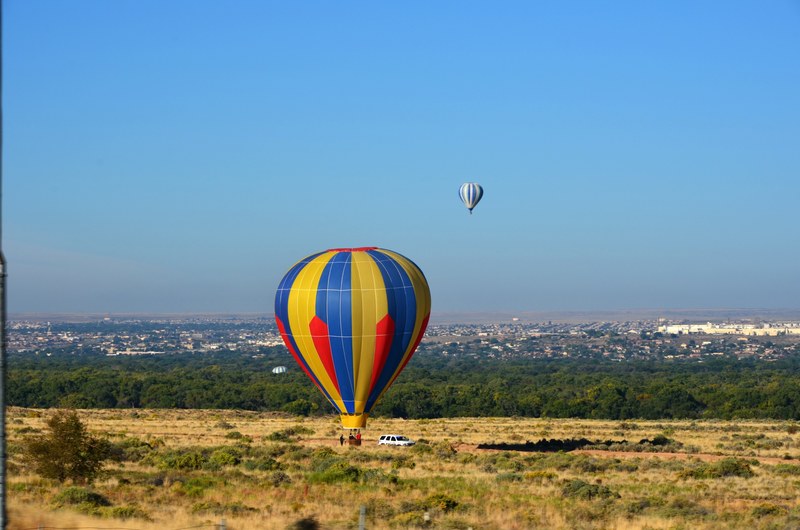 red blue yellow hot air balloon resting on ground with another hot air balloon in distance, touchdown 4k