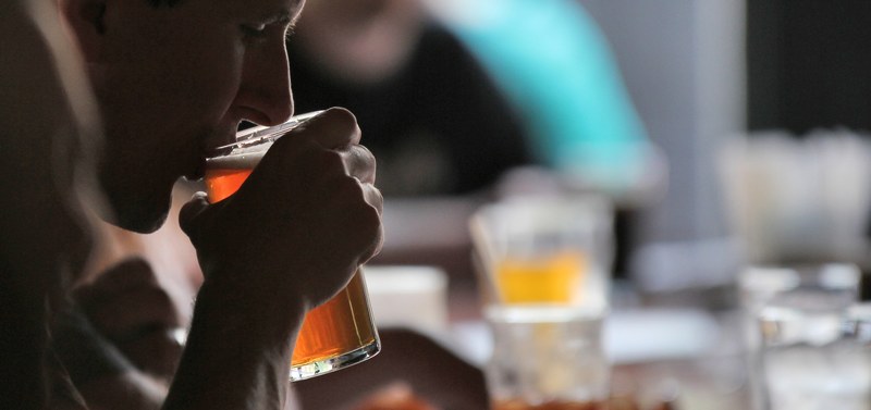 a man holding and drinking a beer from a glass cup in grand rapids brewing co, _man drinking a beer from 4k