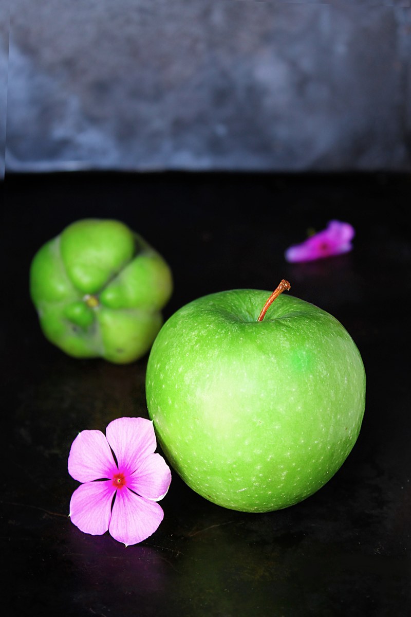 fresh green granny smith apple next to purple flowers and a green fruit, green produce 4k