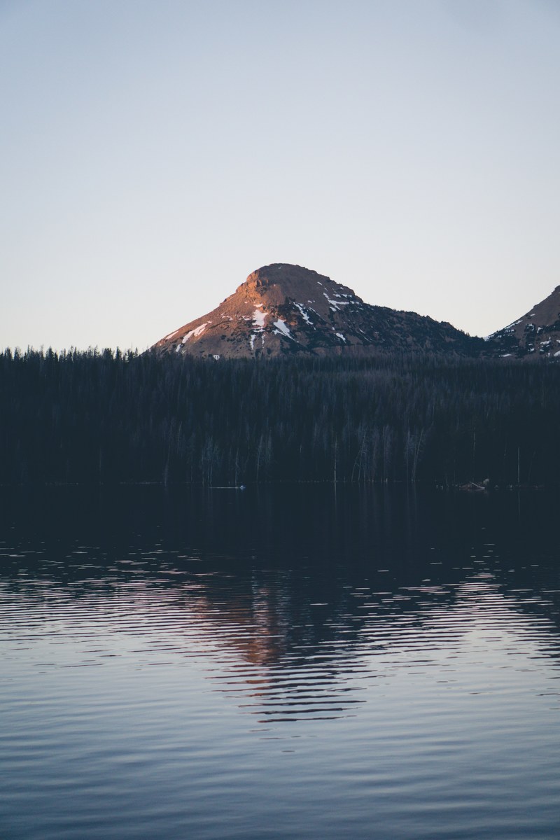 a mountain towering over a tree lined lake, flat mountain over a lake 4k