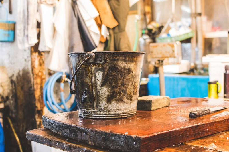 a bucket and a knife on a wooden chopping board in a messy shop, tokyo fish market 4k