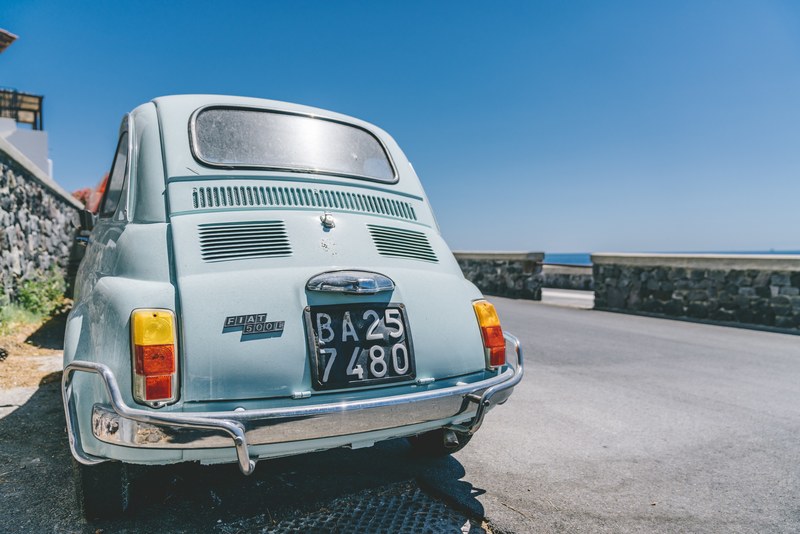 an old model of the fiat 500 is seen parked on a corniche road, _fiat 500 corniche road 4k