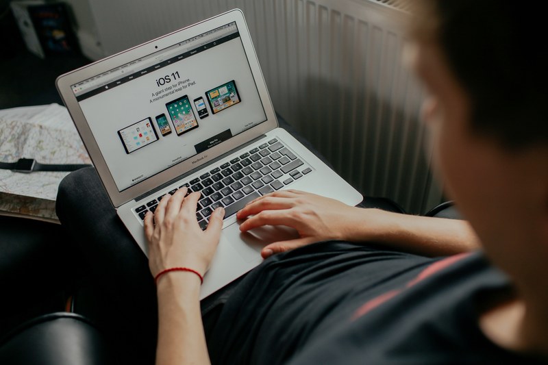 a person holding a macbook with apple website open on their lap, apple fan 4k