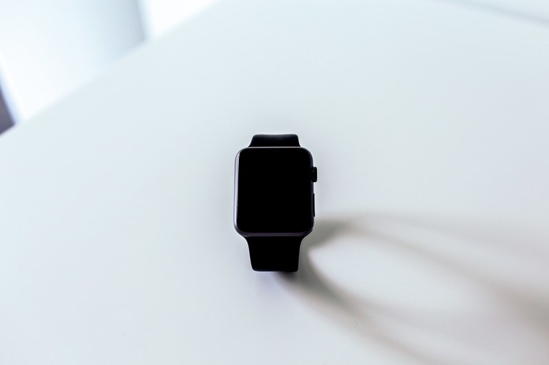 apple wrist watch with a black screen sits on a white surface and casts a shadow, black apple watch on table 4k