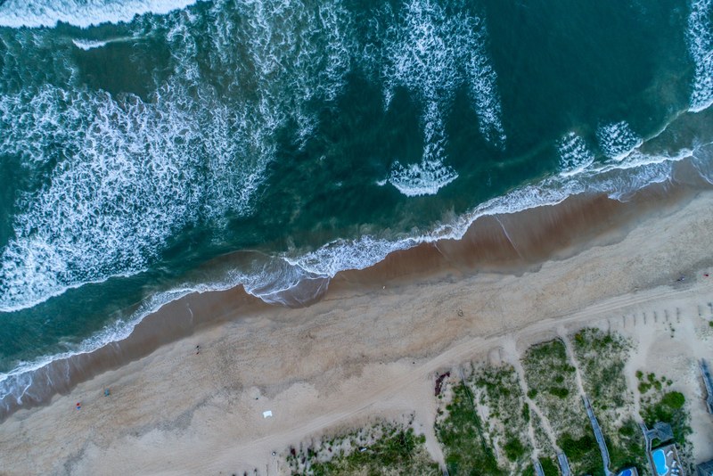 drone aerial view of the ocean washing on the sand beach shore at nags head north carolina united states, ocean waves drone view 4k
