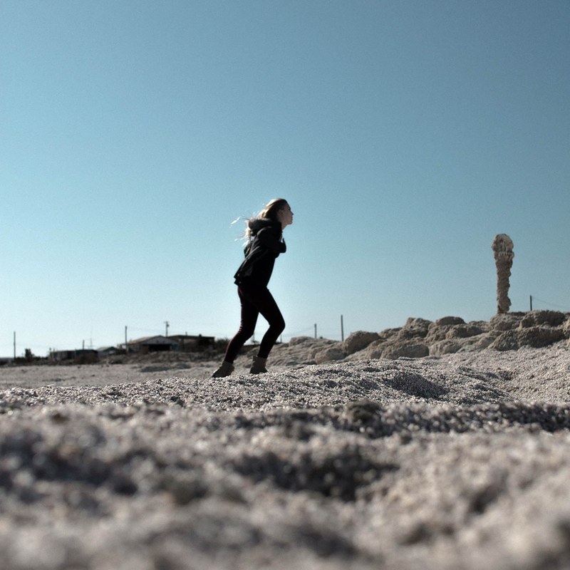 woman dressed in black on the fine pebble beach, woman on a pebble beach 4k