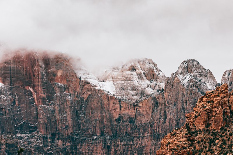 red and orange rocky mountains on a foggy day in zion national park, rocky cliffs in fog 4k