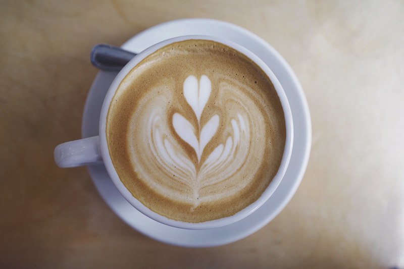 a cup of coffee with a leaf painted in the milk at two hands cafe, two hands cafe latte art 4k
