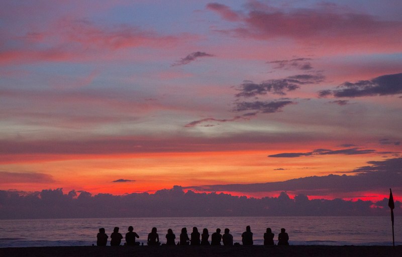 thirteen people are silhouetted against a setting sun coloring the sky vibrantly, group of colors 4k
