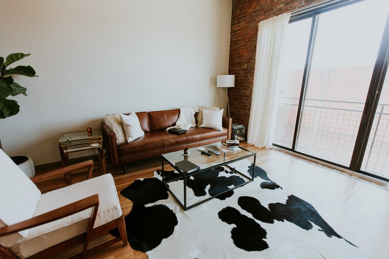 living room interior with animal print rug couch chair and large sliding door and brick wall, mid century loft 4k