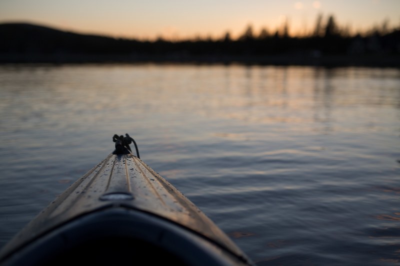 the front of a canoe floating in the river covered with water droplets at sunset or sunrise, canoe at sunrise 4k