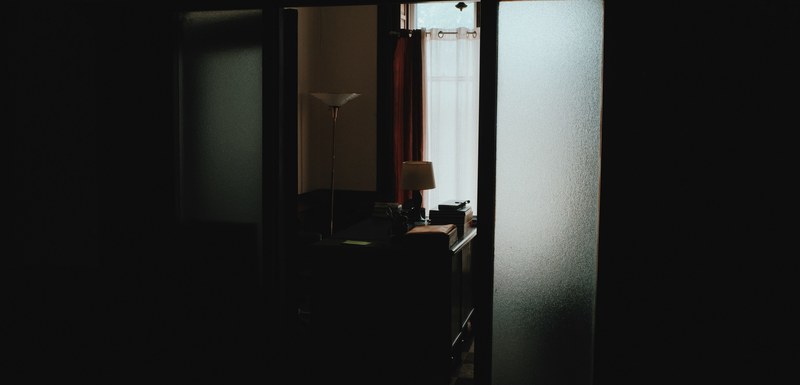dark hallway leading to office with desk and lamp, empty room 4k