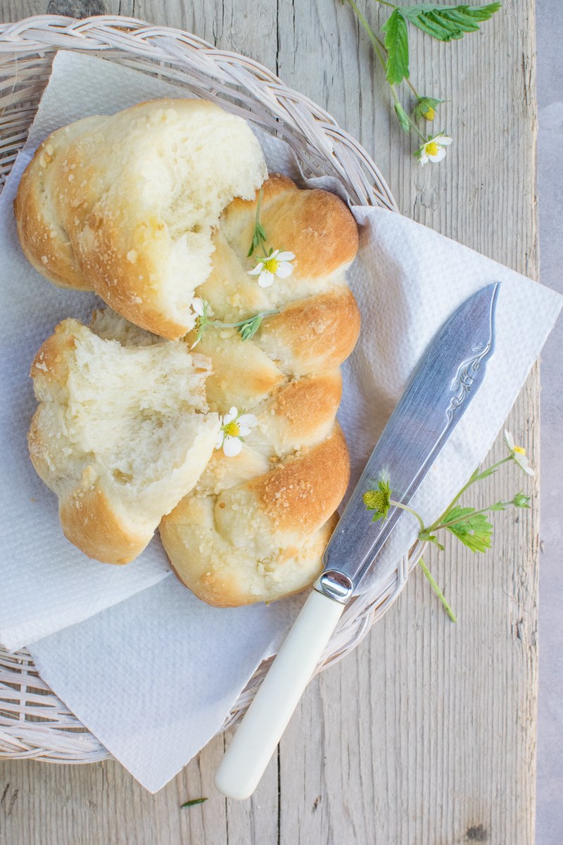 two loaves of braided bread one half eaten on a basket beside a breadknife, yummy buns 4k