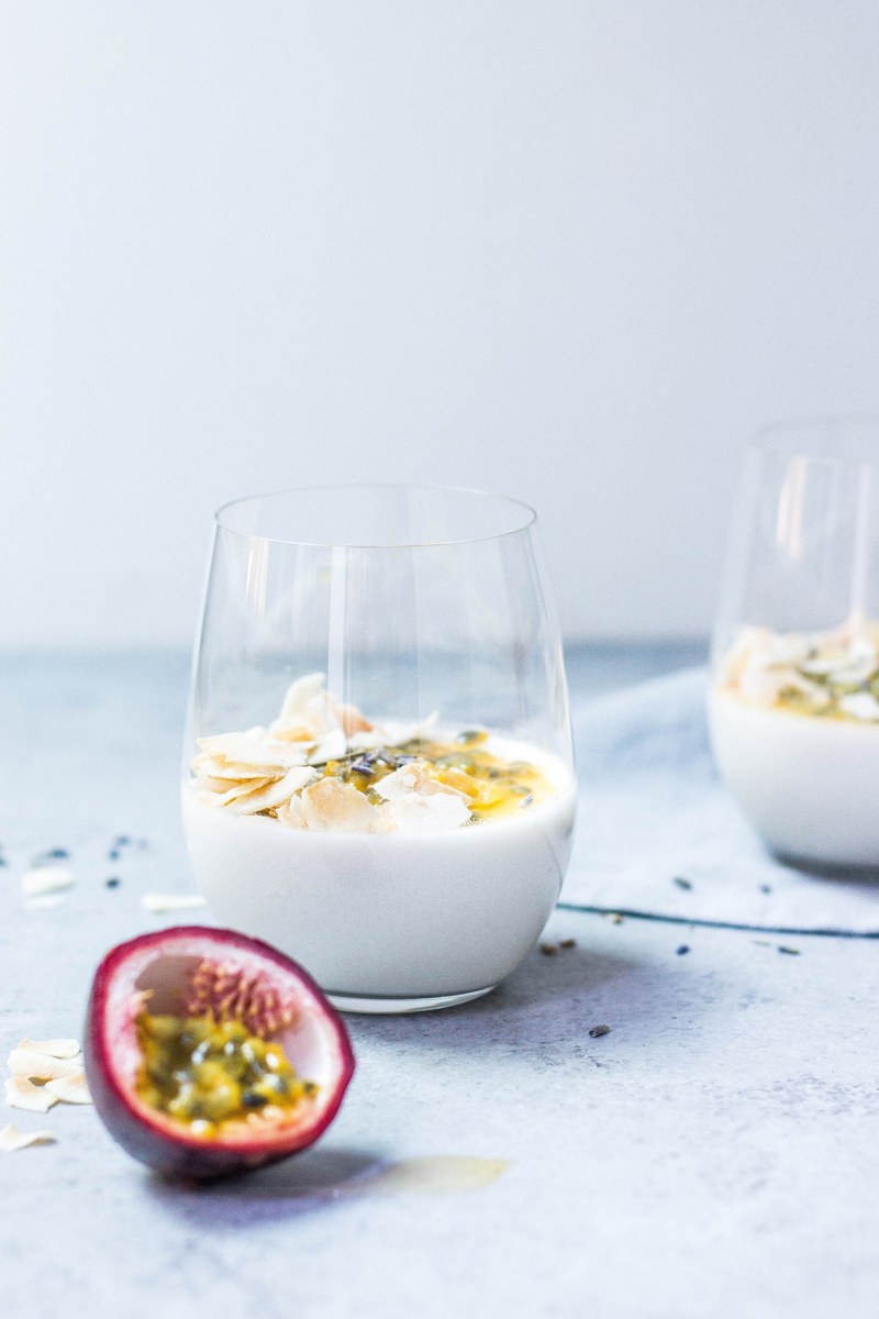 a cut half of a passion fruit next to glasses with yogurt with dried fruit, coconut amp passion fruit panna cotta 4k