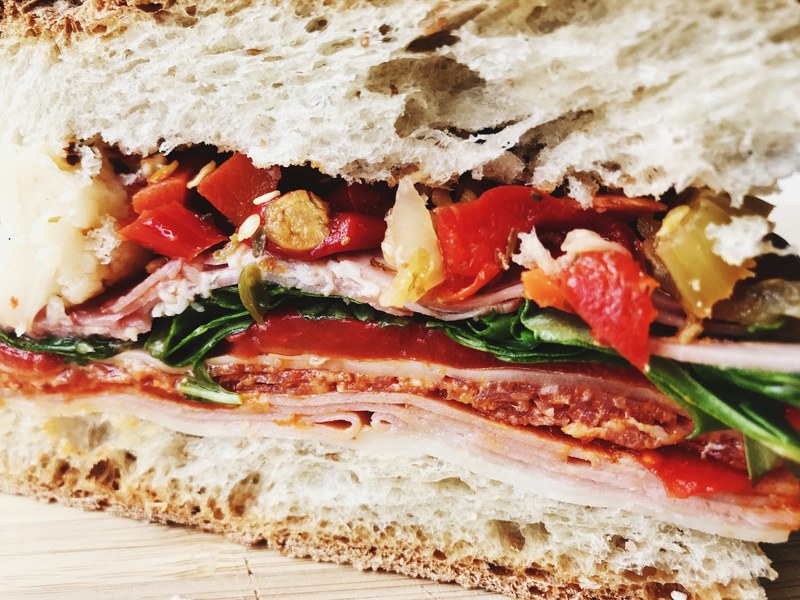 macro of a sliced sandwich with tomatoes sliced cold cuts greens and cheese, up close and personal 4k