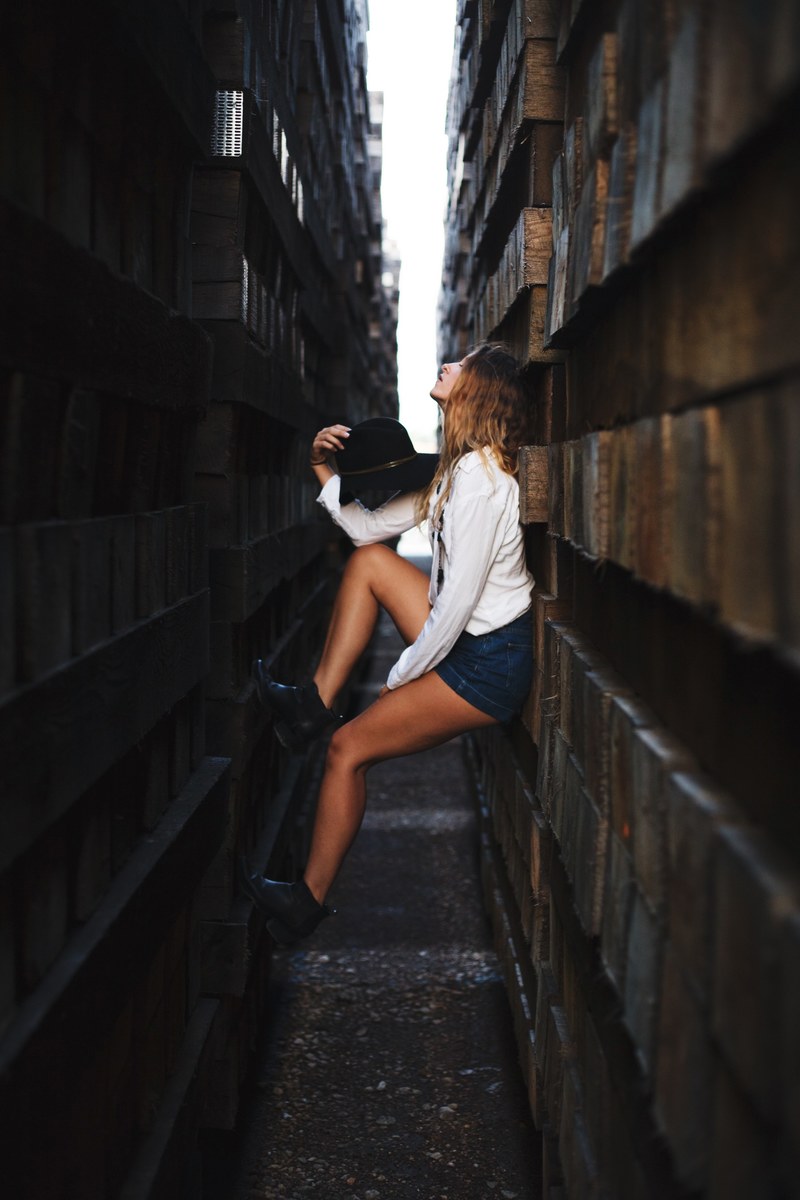 a woman in a white shirt leans in a narrow space between two dark walls, caught in between 4k