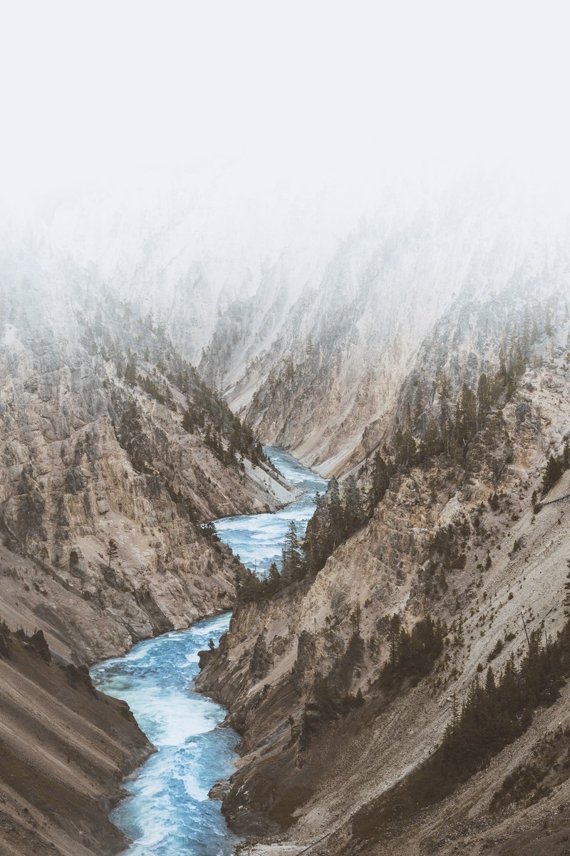a river rushes through the valley of deserted mountain sides in yellowstone, whos in for a boat ride 4k