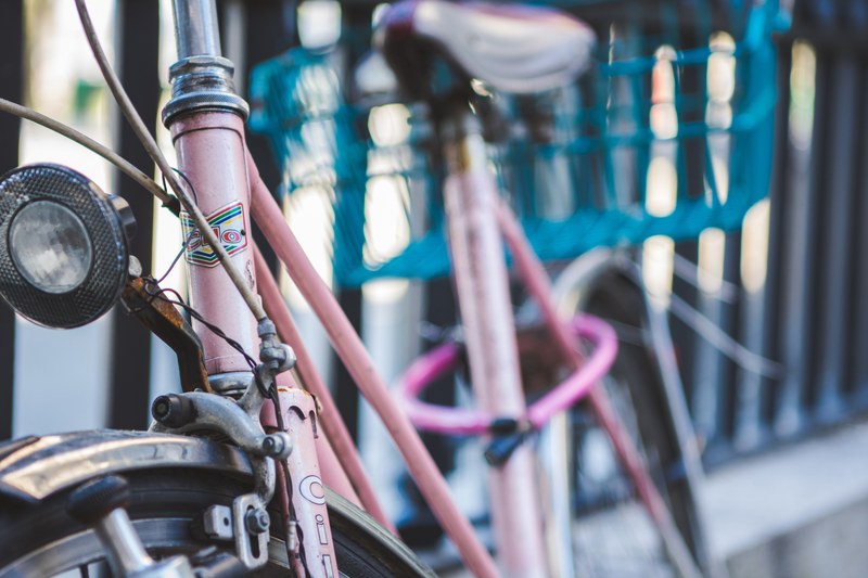 a pink bicycle with a blue basket leaning against a railing in bern, parked pink bicycle 4k